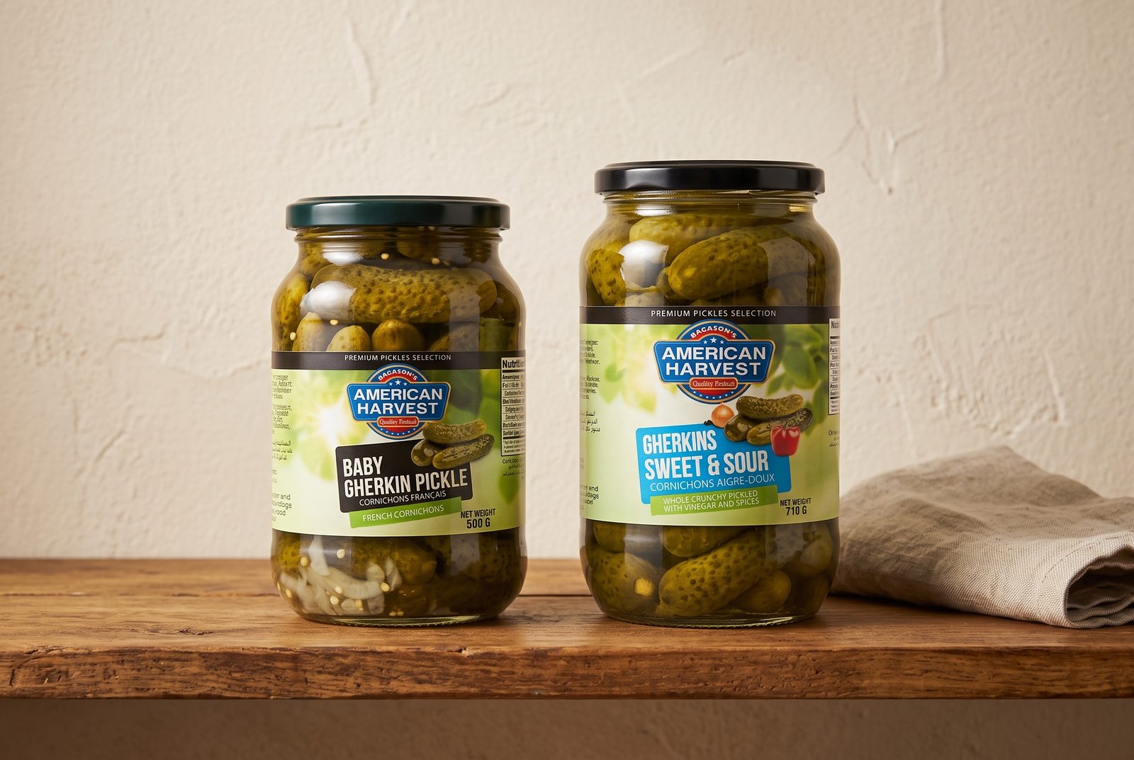 Jars of American Harvest Baby Gherkin Pickle and Gherkins Sweet & Sour standing on a wooden pantry shelf
